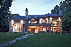Transitional style lake house with stone exterior and covered outdoor entertaining area.