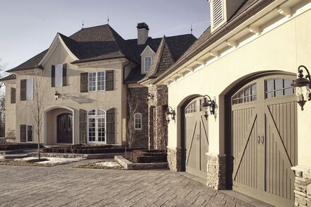 European country style home with stucco exterior and arch carriage garage doors.
